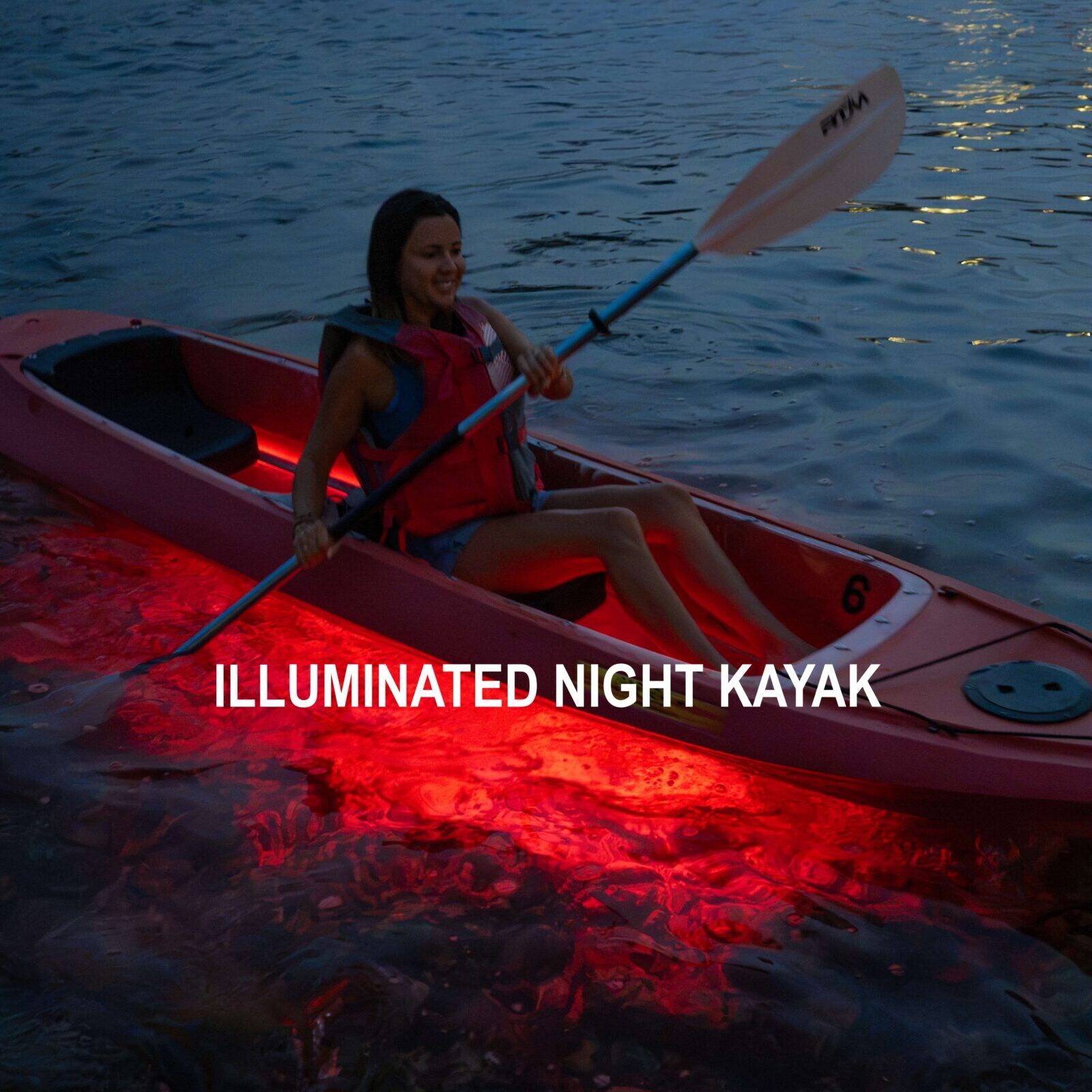 Guests paddling illuminated kayaks through calm tropical waters at night